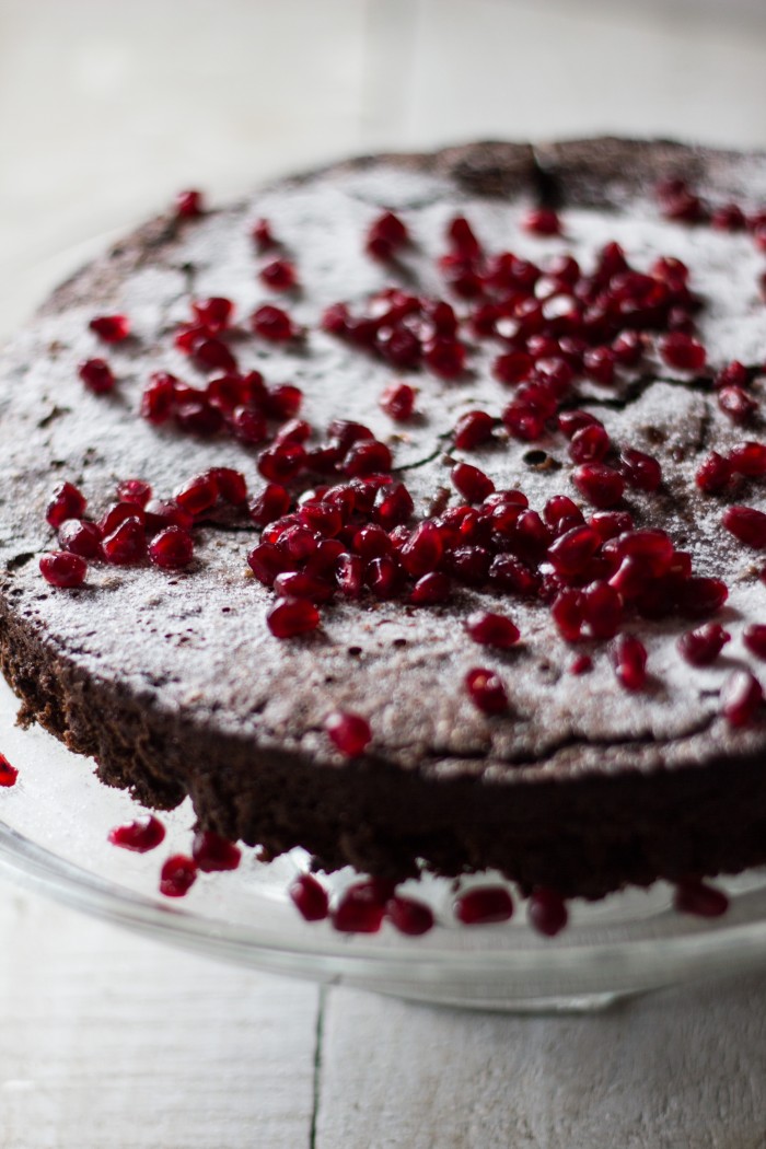 decadent flourless chocolate cake covered in sweet pomegranate seeds, all lightly dusted with icing sugar